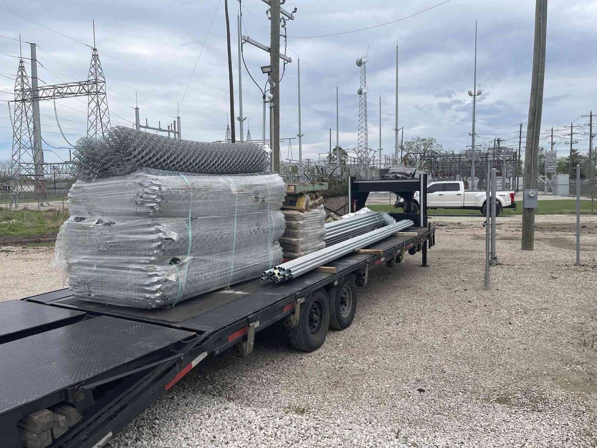 Trailer loaded with chain link fencing, posts, and concrete at a substation