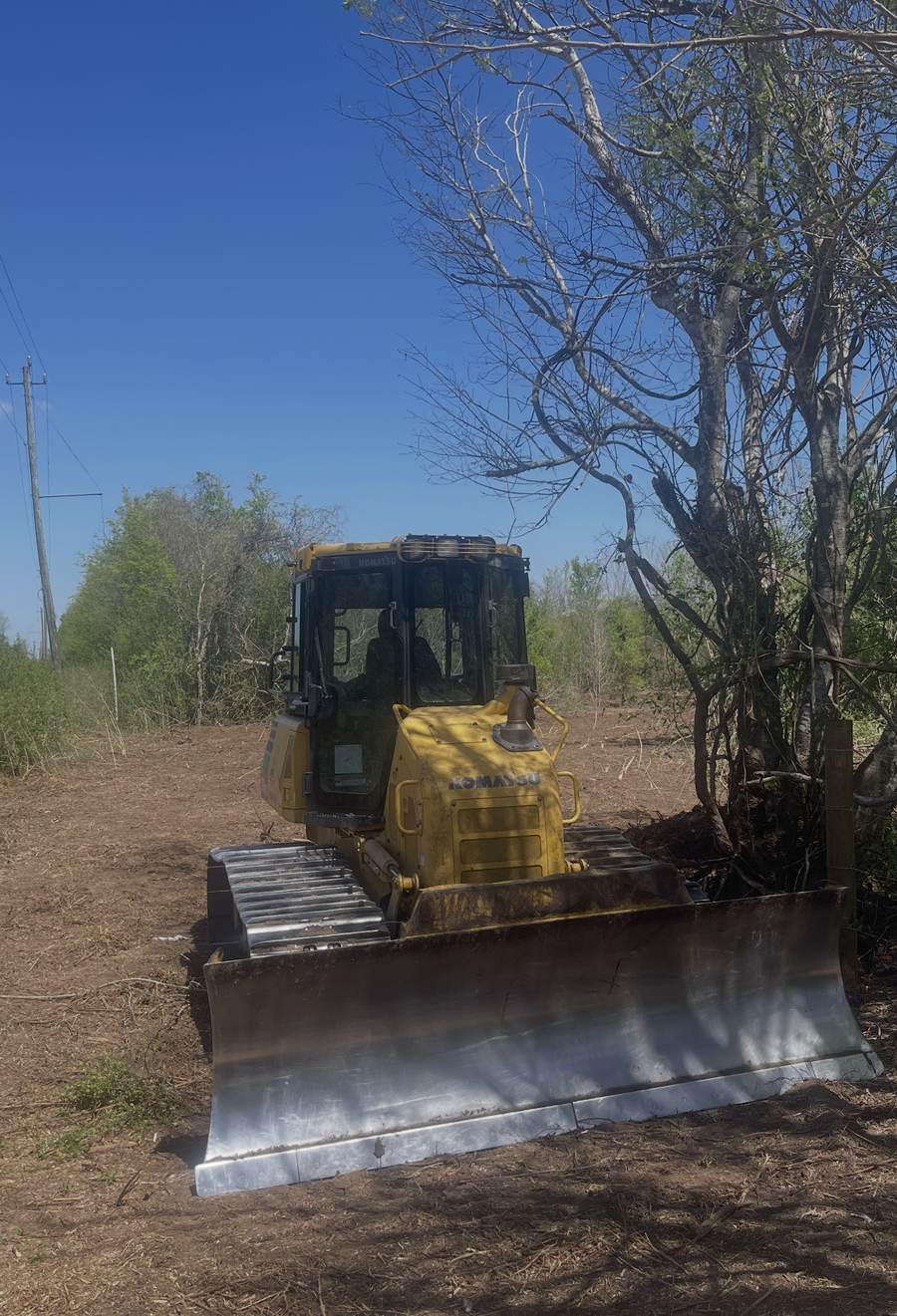 Komatsu dozer on a freshly cleared strip beside a power line