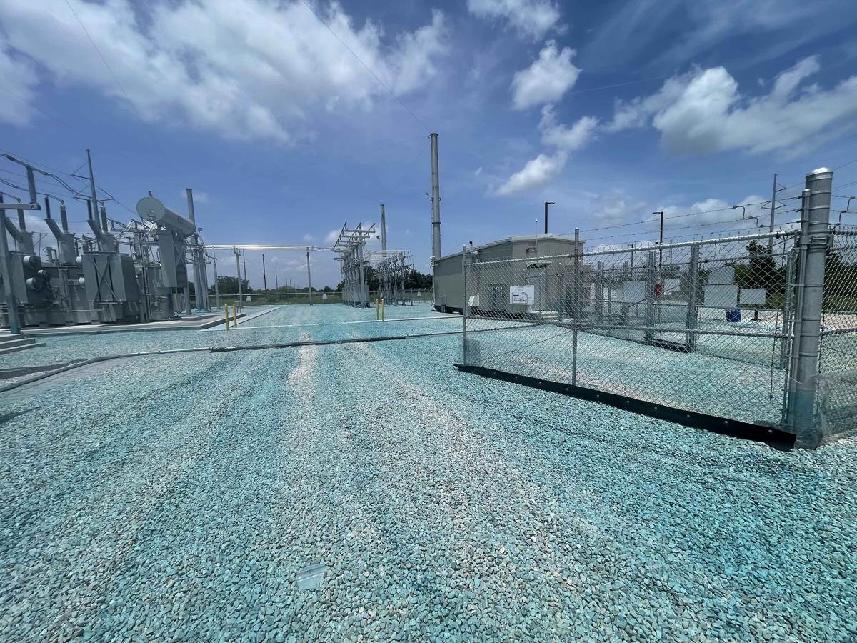 Inside a substation yard with transformers, steel structures, and a control building