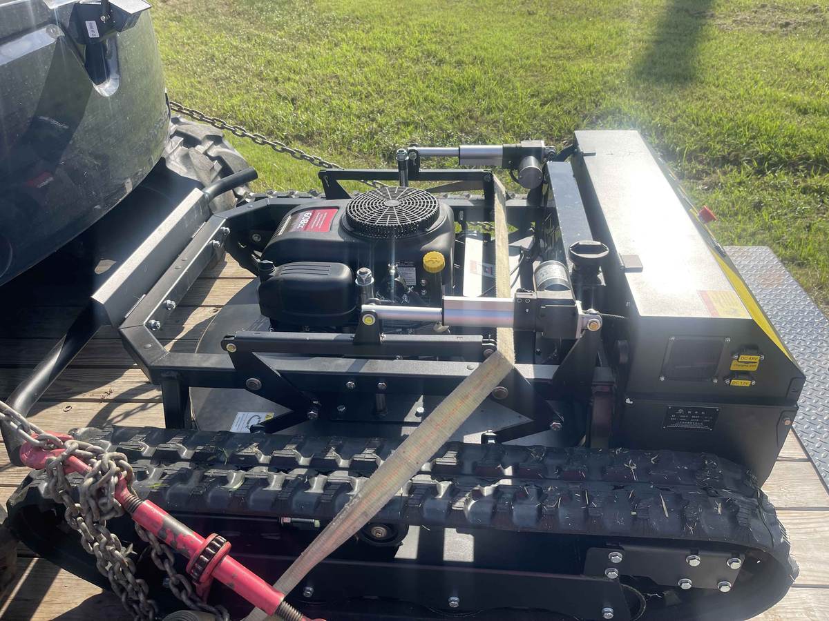 Tracked mower strapped down on a trailer, ready to haul